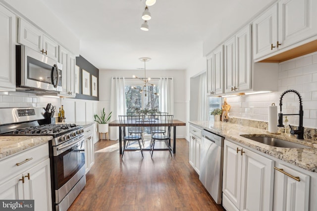 kitchen featuring dark wood-style flooring, a sink, white cabinets, appliances with stainless steel finishes, and backsplash