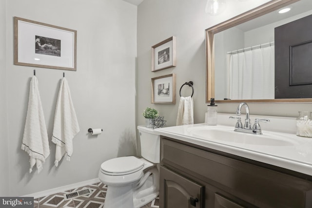 bathroom with vanity, toilet, and baseboards