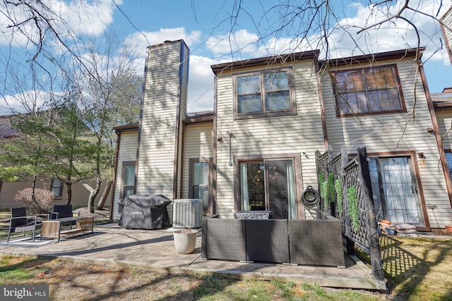 back of property with outdoor lounge area, a chimney, and a patio area