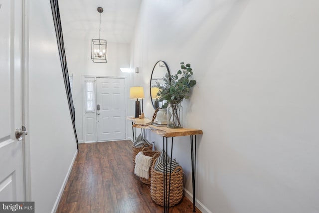 foyer featuring an inviting chandelier, baseboards, and dark wood finished floors