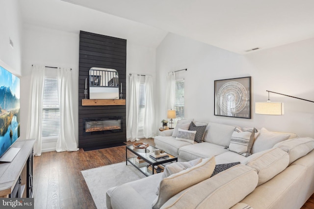 living room featuring high vaulted ceiling, a large fireplace, visible vents, and wood-type flooring