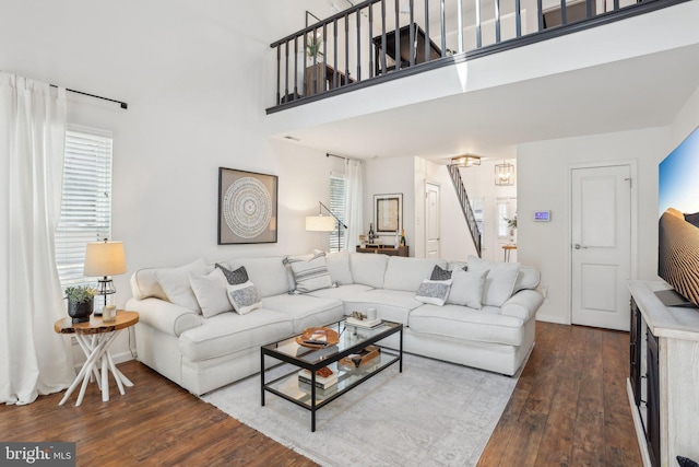 living room featuring baseboards, a high ceiling, stairway, and wood finished floors