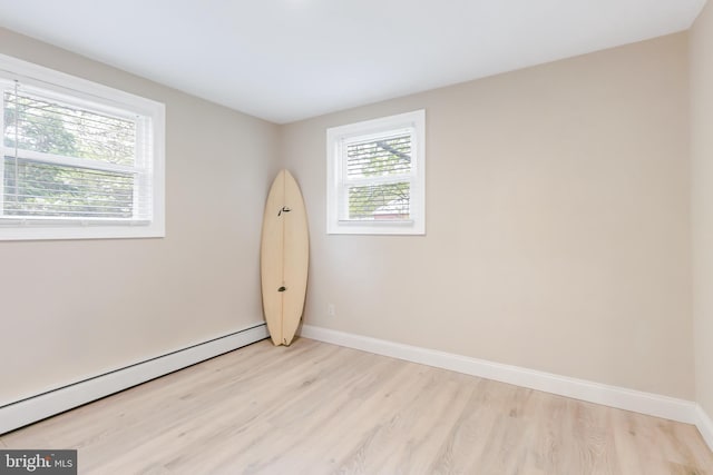 unfurnished room with light wood-type flooring, baseboards, and a baseboard radiator