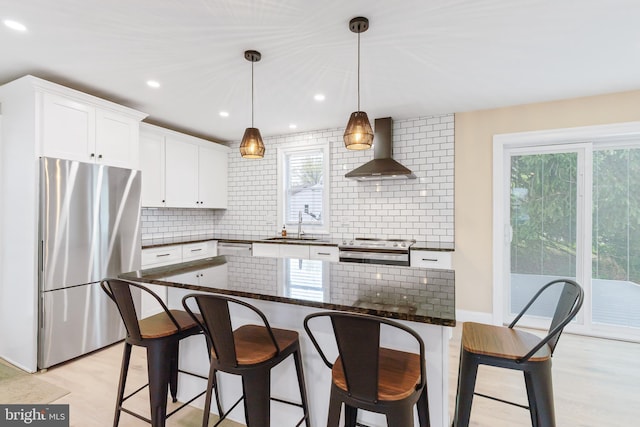 kitchen featuring wall chimney exhaust hood, stainless steel appliances, a wealth of natural light, and backsplash