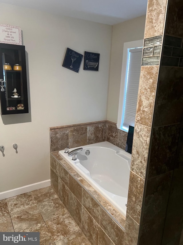 bathroom featuring baseboards and a bath