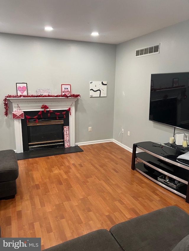 living room with baseboards, visible vents, wood finished floors, a fireplace, and recessed lighting