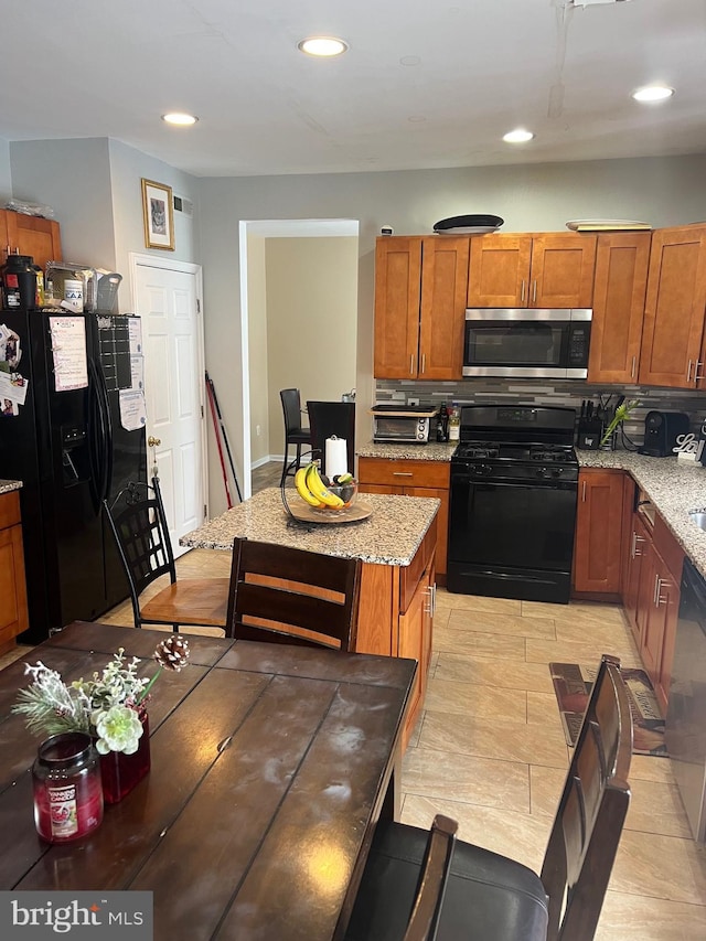 kitchen featuring light stone countertops, recessed lighting, brown cabinets, decorative backsplash, and black appliances