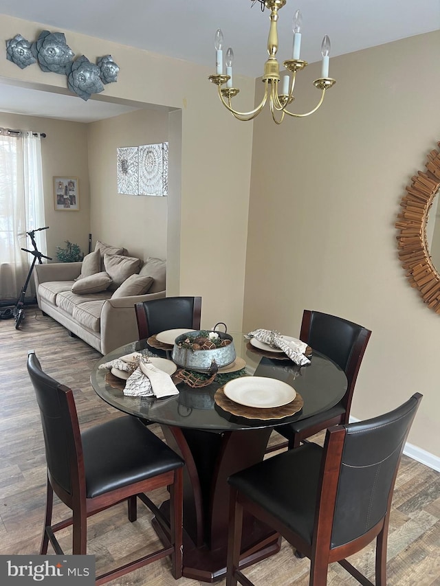 dining room featuring a chandelier, baseboards, and wood finished floors