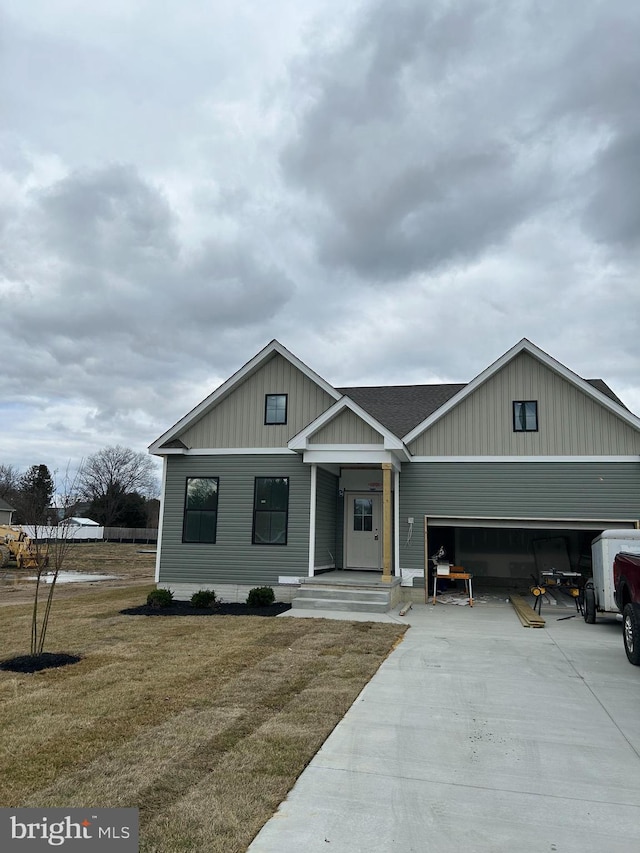 view of front of house with driveway, an attached garage, roof with shingles, and a front yard