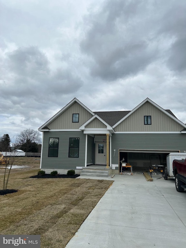 view of front of home with a front yard, concrete driveway, roof with shingles, and an attached garage