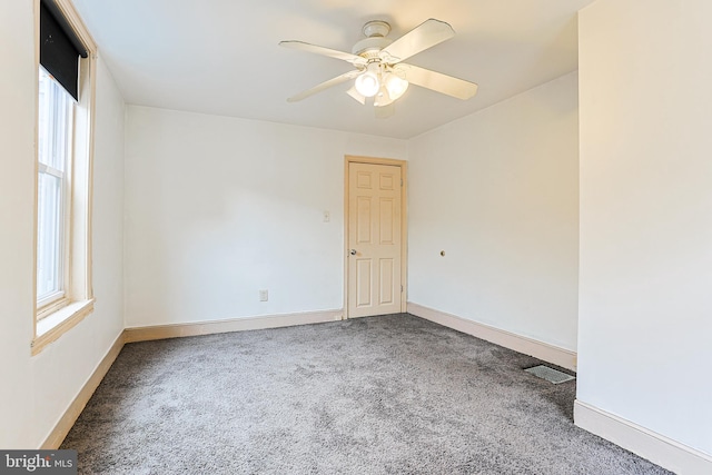 unfurnished room featuring carpet floors, visible vents, baseboards, and a ceiling fan