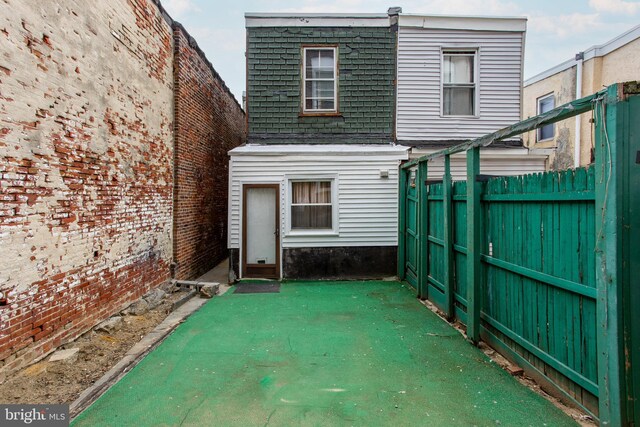 rear view of property with fence, mansard roof, and roof with shingles