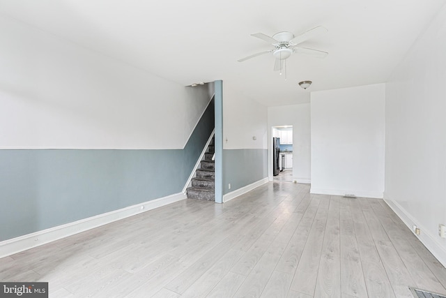 unfurnished room with wood finished floors, visible vents, a ceiling fan, stairs, and baseboards