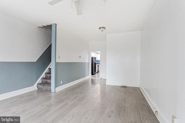 empty room featuring stairway, wood finished floors, a ceiling fan, and baseboards