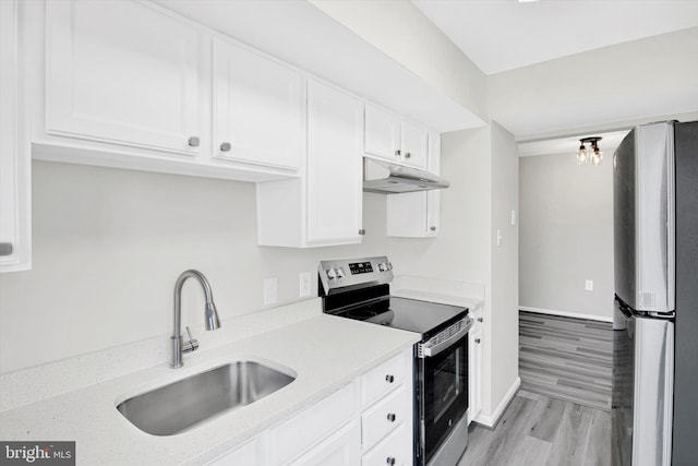 kitchen with under cabinet range hood, stainless steel appliances, a sink, white cabinetry, and light countertops