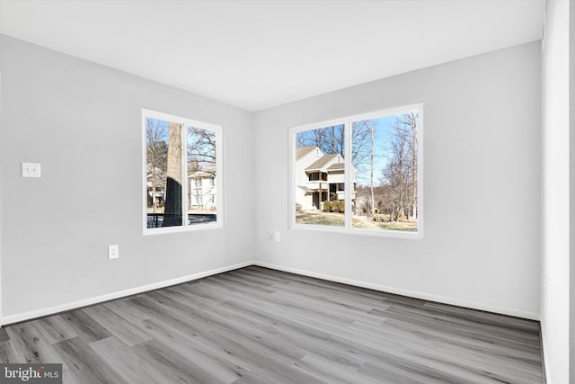 spare room featuring baseboards, a wealth of natural light, and wood finished floors