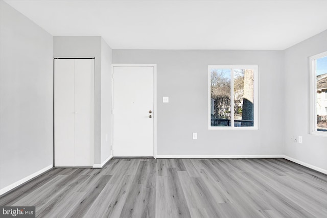 unfurnished bedroom featuring a closet, multiple windows, wood finished floors, and baseboards