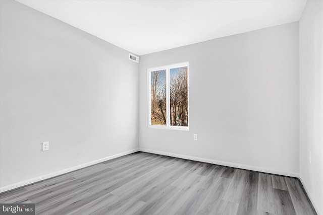 spare room featuring wood finished floors, visible vents, and baseboards