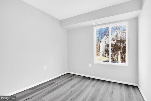 empty room with baseboards, visible vents, and wood finished floors