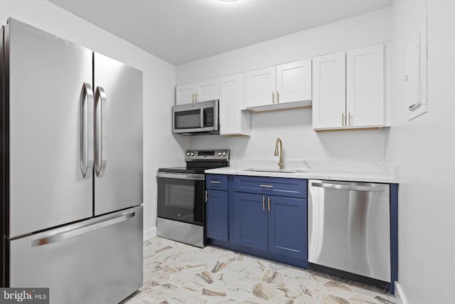 kitchen with white cabinets, blue cabinetry, stainless steel appliances, and a sink