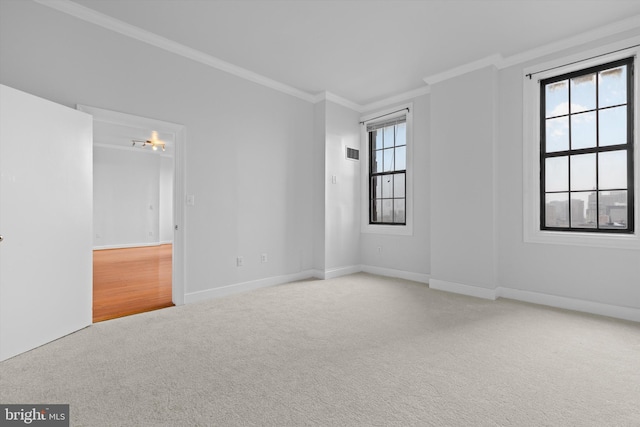 empty room with ornamental molding, a healthy amount of sunlight, carpet flooring, and baseboards