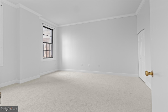 carpeted spare room featuring baseboards and crown molding