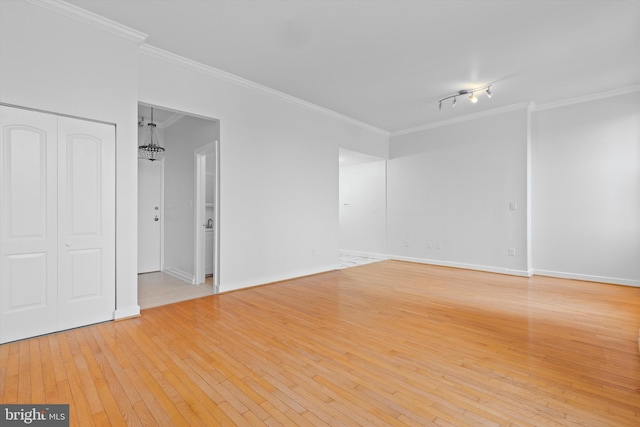 empty room with light wood-style floors, baseboards, and ornamental molding