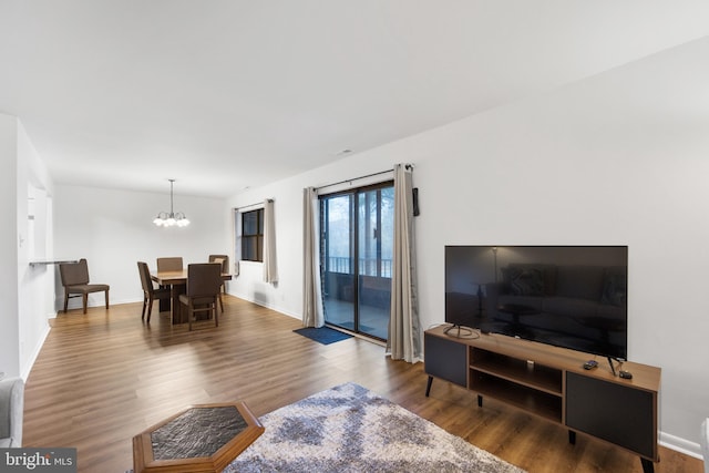 living room featuring baseboards, wood finished floors, and a notable chandelier