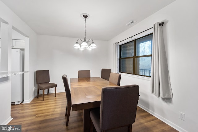 dining area with a chandelier, visible vents, baseboards, and wood finished floors