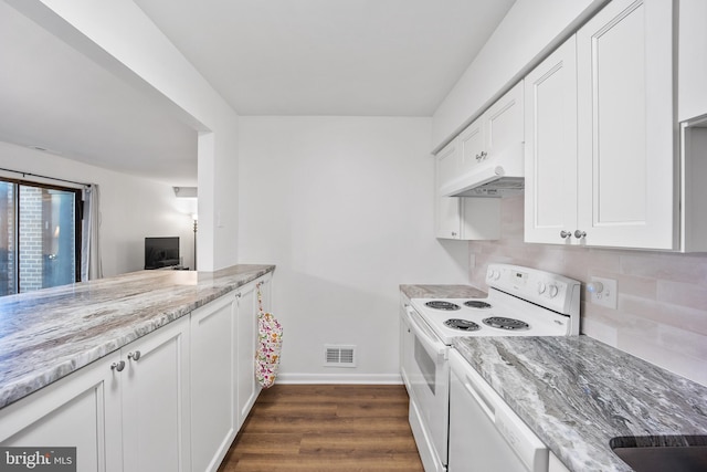 kitchen featuring light stone counters, under cabinet range hood, white appliances, visible vents, and dark wood finished floors