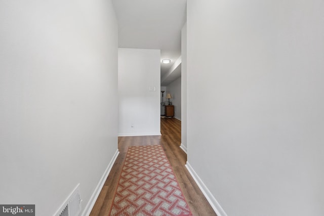 hall featuring wood finished floors, visible vents, and baseboards