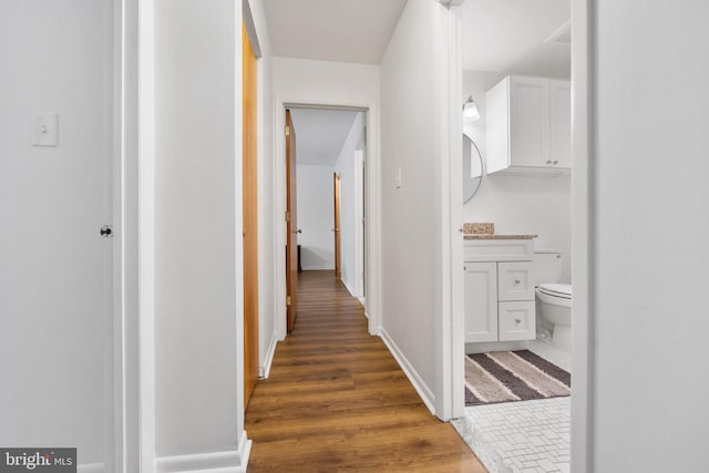 hallway featuring baseboards and wood finished floors