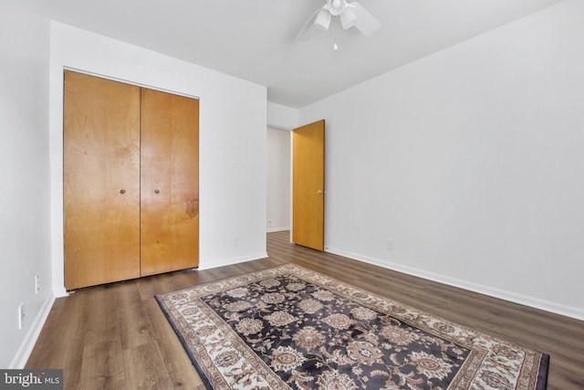 unfurnished bedroom featuring a ceiling fan, a closet, baseboards, and wood finished floors