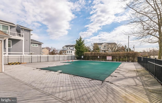 community pool with a patio, fence, and a residential view