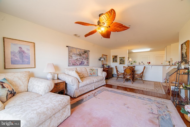 living room featuring ceiling fan, visible vents, and wood finished floors