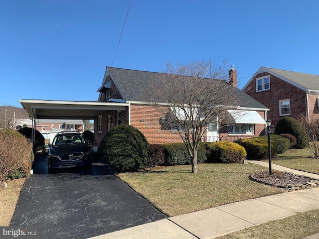 view of front of home featuring a carport, aphalt driveway, brick siding, and a front yard