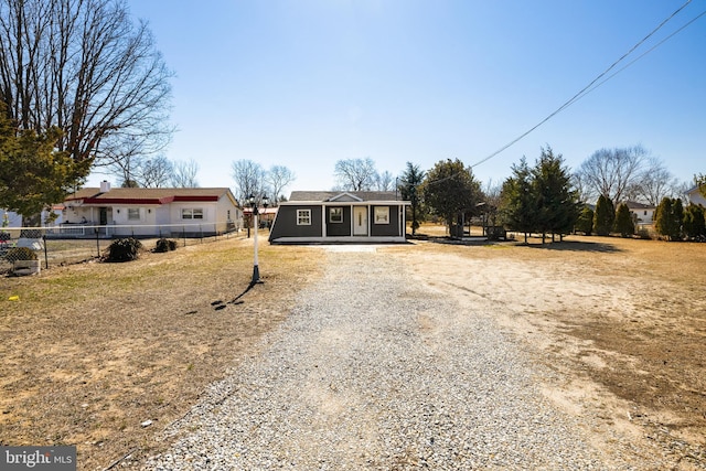 view of front of home featuring gravel driveway, fence, and an outdoor structure