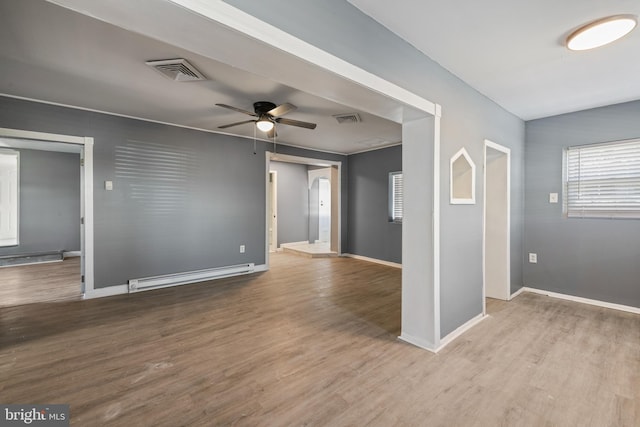 spare room featuring a baseboard radiator, wood finished floors, visible vents, and a ceiling fan