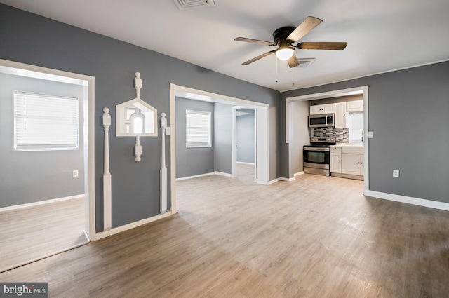 unfurnished living room with light wood-style floors, baseboards, visible vents, and a ceiling fan