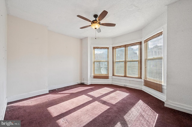 carpeted spare room with a ceiling fan, baseboards, and a textured ceiling