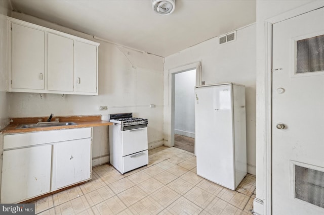 kitchen featuring a sink, visible vents, white appliances, and white cabinets