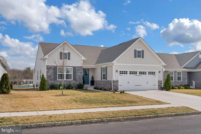 view of front facade with driveway, a garage, stone siding, a front lawn, and board and batten siding