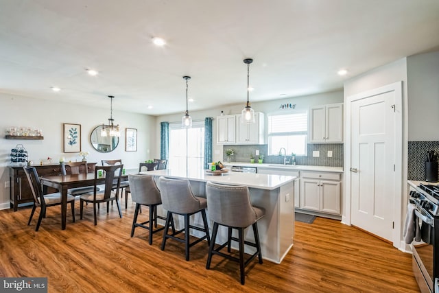 kitchen with stainless steel gas range oven, dark wood-style floors, a kitchen island, a breakfast bar, and a sink