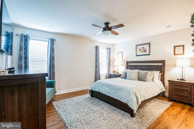 bedroom with multiple windows, ceiling fan, baseboards, and wood finished floors