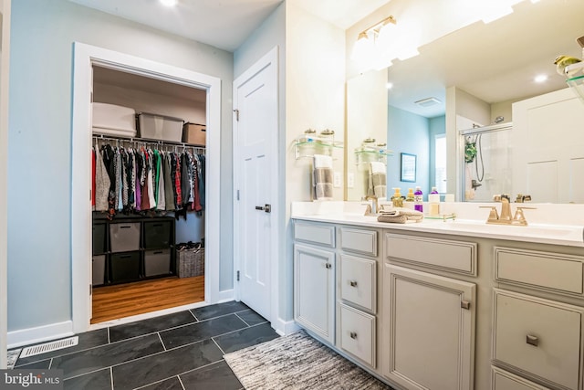 full bath featuring double vanity, a spacious closet, a sink, a shower stall, and tile patterned floors