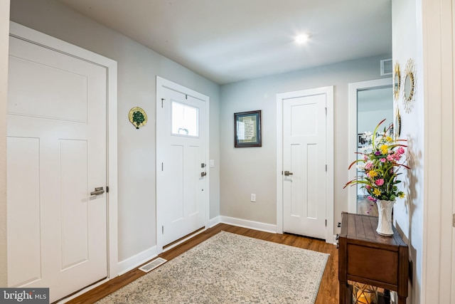 foyer entrance featuring dark wood-type flooring, visible vents, and baseboards