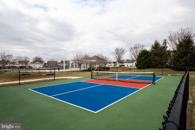 view of tennis court with a residential view and fence