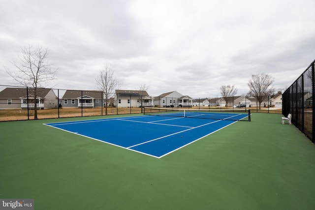 view of tennis court featuring a residential view and fence