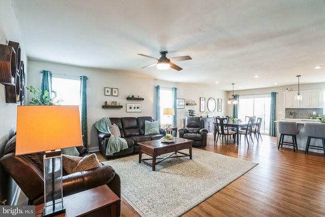 living area with a healthy amount of sunlight, ceiling fan, wood finished floors, and recessed lighting