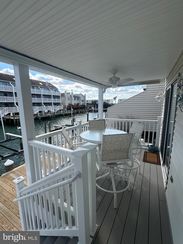 deck with a ceiling fan, outdoor dining space, and a water view